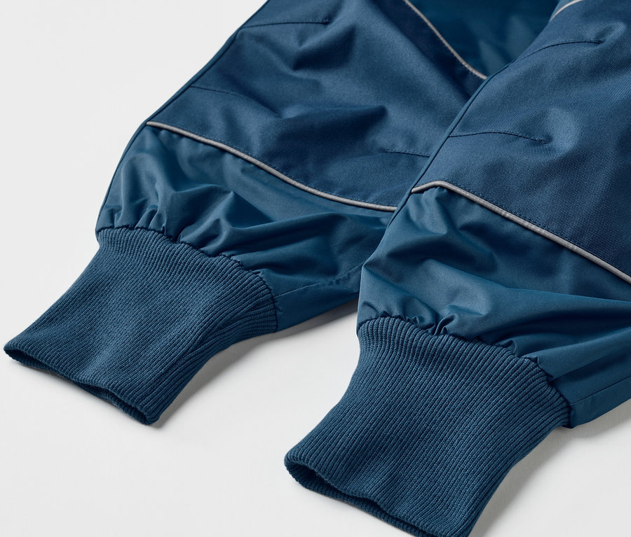 Gros plan sur un pantalon de pluie évolutif pour enfant, de couleur bleue.