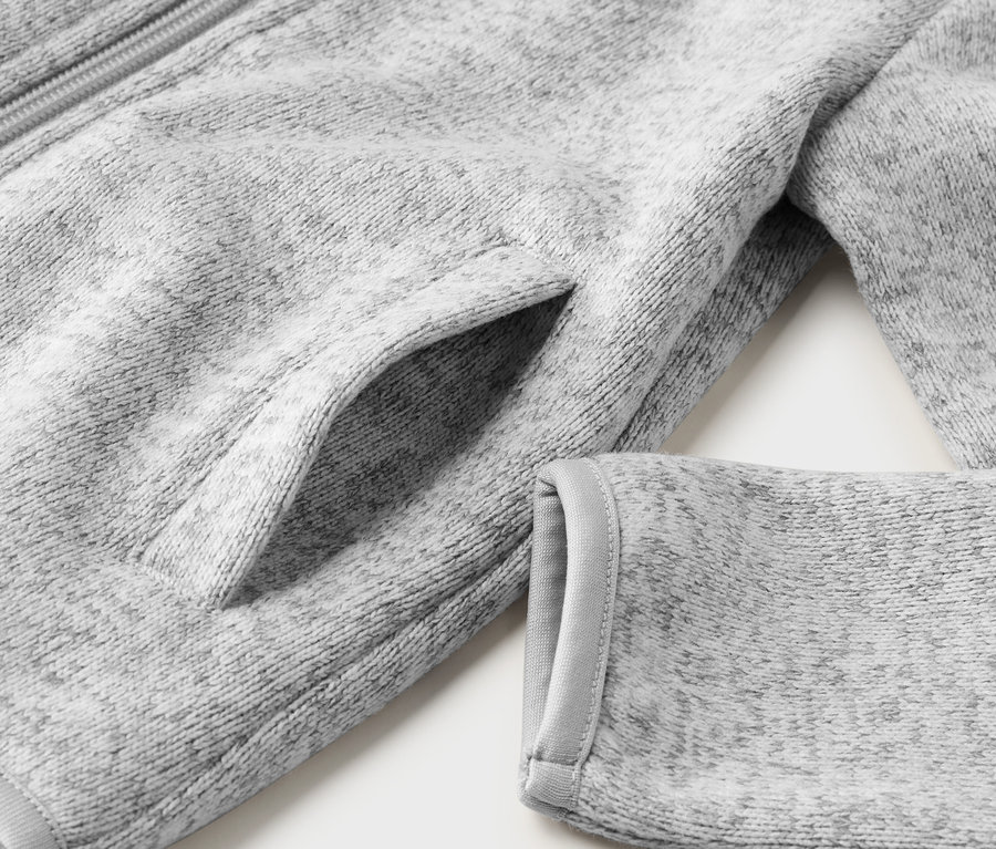 Gros plan sur une veste en maille polaire grise pour enfant, montrant une poche et une manche.