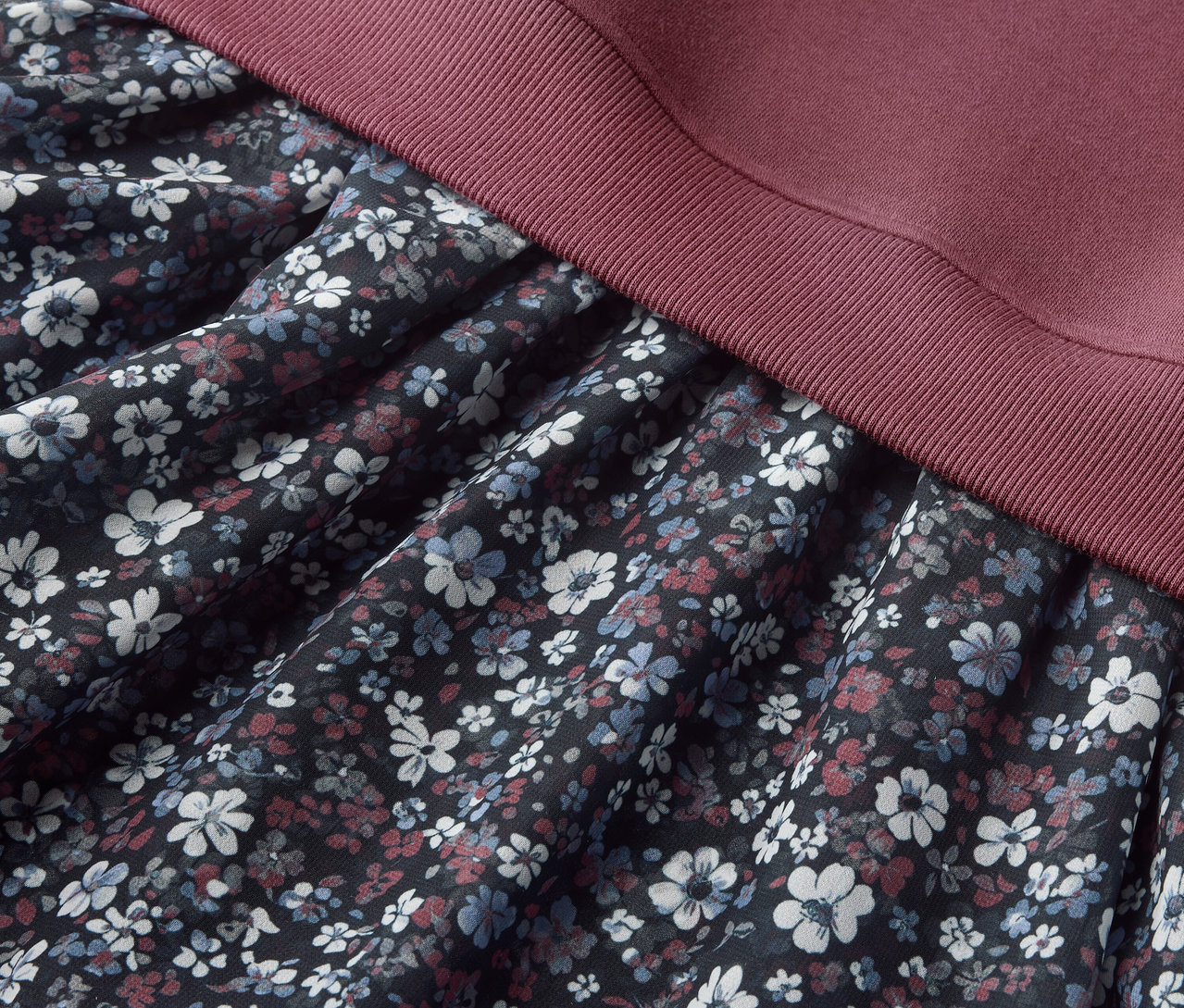Vue détaillée d'une Kinder-Sweatkleid avec un motif floral sur la jupe et un haut bordeaux.