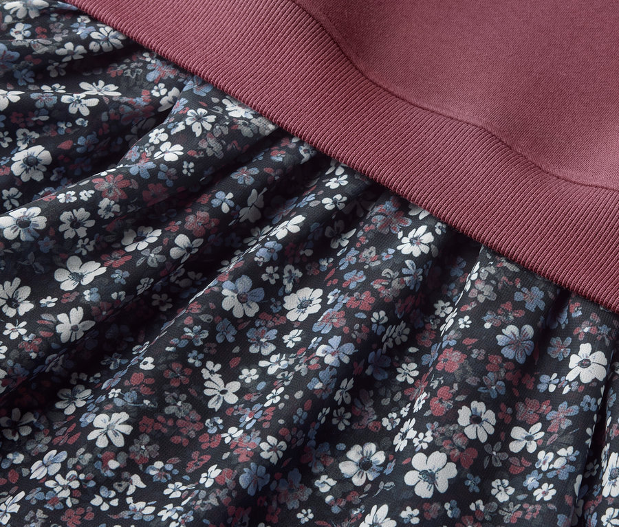 Vue détaillée d'une Kinder-Sweatkleid avec un motif floral sur la jupe et un haut bordeaux.