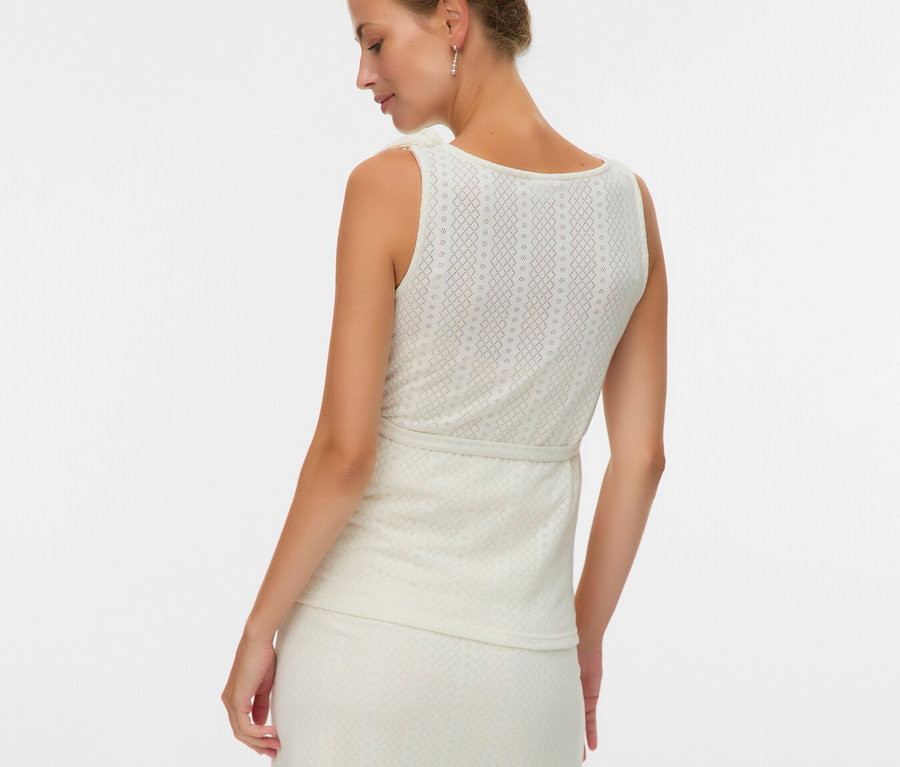 Femme de dos portant un haut sans manches et une jupe à motifs.