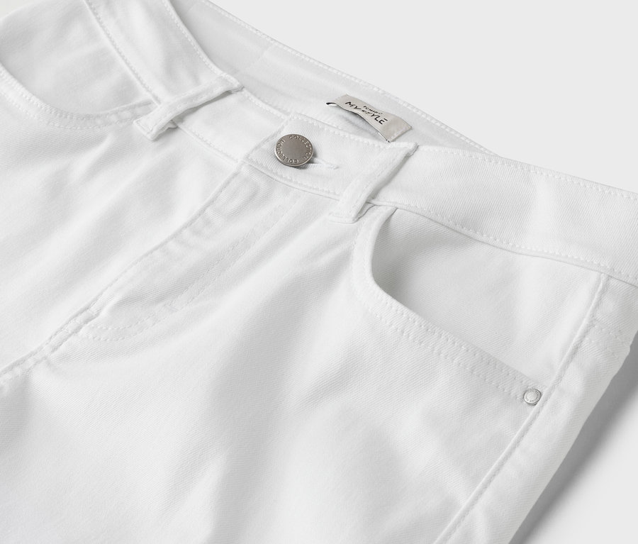 Gros plan d'un pantalon blanc avec bouton et poche.
