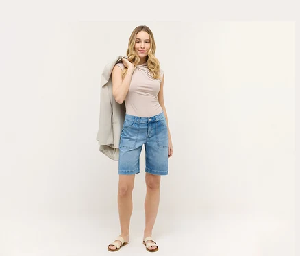 Femme portant un haut beige et un short bleu Angels Denim «
Lia Urban
». Elle a un blazer sur l’épaule.