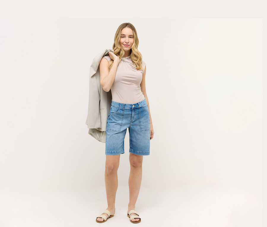 Femme portant un haut beige et un short bleu Angels Denim «
Lia Urban
». Elle a un blazer sur l’épaule.