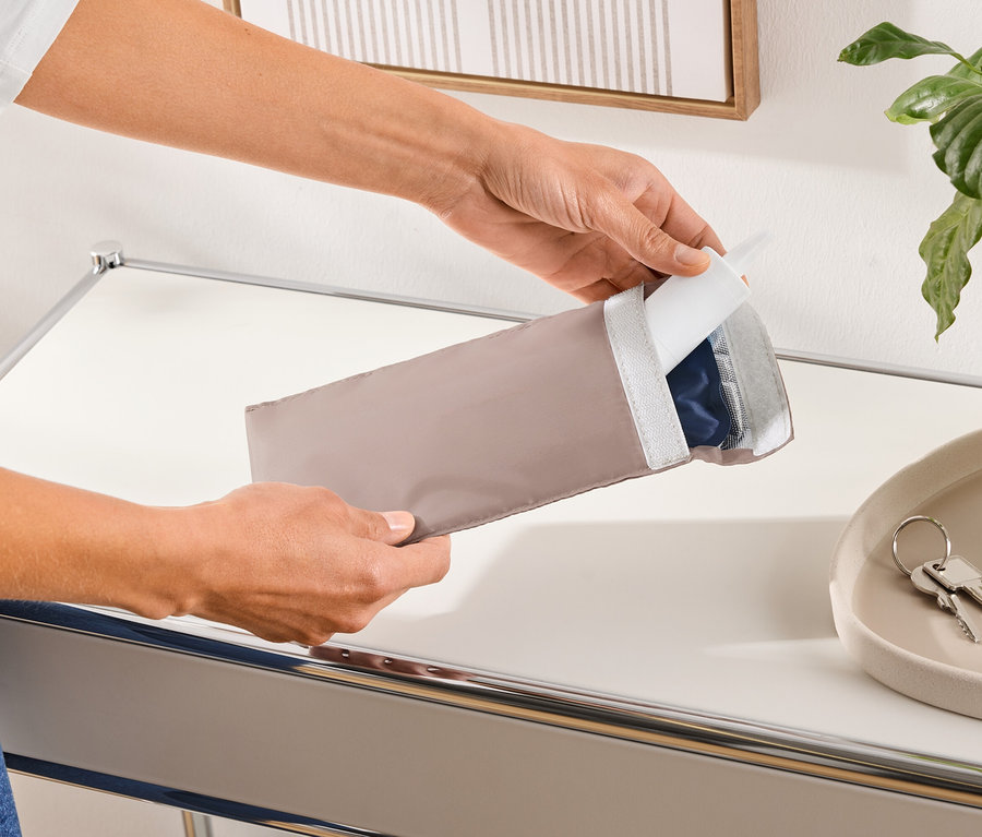 Une personne ouvre un étui de protection allongé beige contenant un produit bleu.