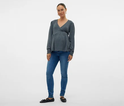 Femme portant un chemisier cache-cœur gris et un Jeans Skinny MAMALICIOUS «
MLMILA », posant sur fond blanc.