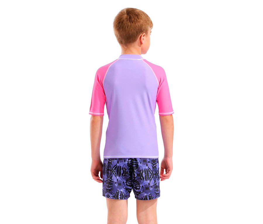 Vue arrière d'un enfant blond portant un t-shirt de rashguard violet et rose et un short de bain violet à motifs.