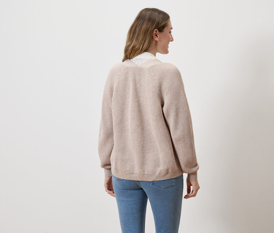 Femme de dos en jean et cardigan beige sur fond blanc.