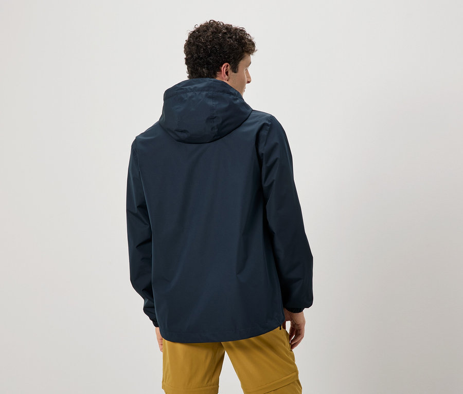 Vue arrière d'un homme aux cheveux bouclés portant un imperméable bleu marine à capuche et un pantalon ocre.