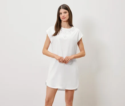 Femme aux cheveux bruns portant une chemise de nuit blanche à manches courtes et col en V.