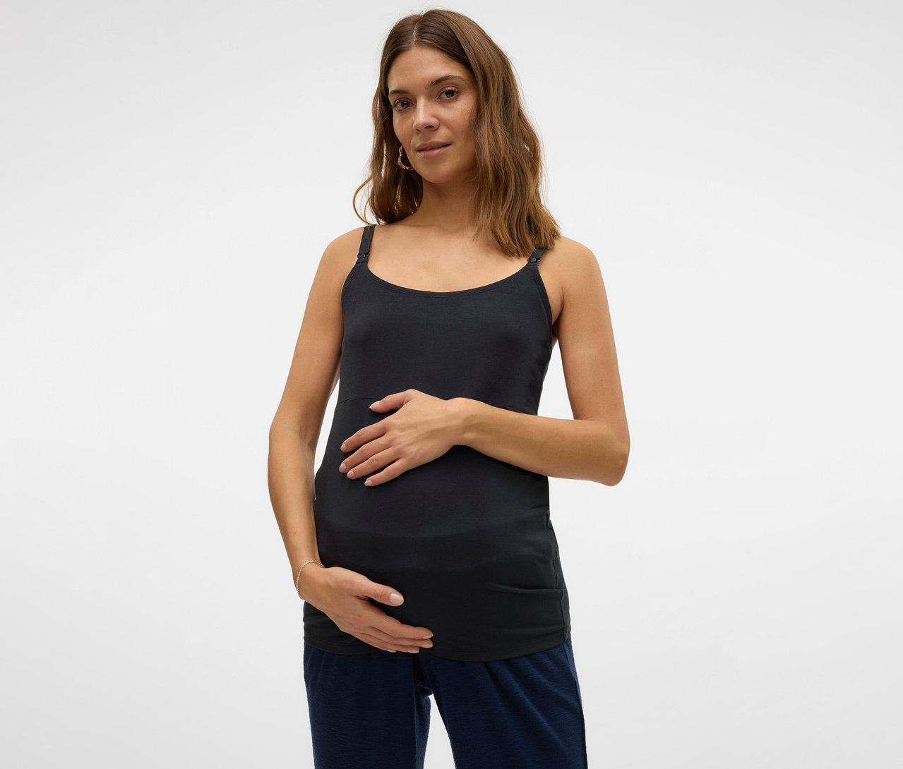 Femme enceinte, les mains sur le ventre, portant un des 2 tops à bretelles spaghetti MAMALICIOUS « MLKERRIE ».