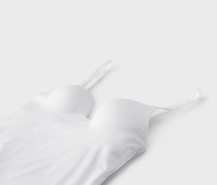 Gros plan d'un bustier blanc à fines bretelles sur fond blanc.