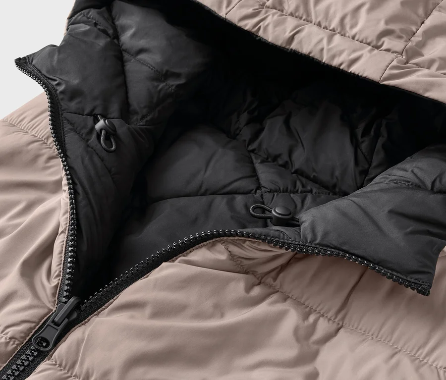 Gros plan d'une doudoune beige ouverte avec doublure noire et capuche.