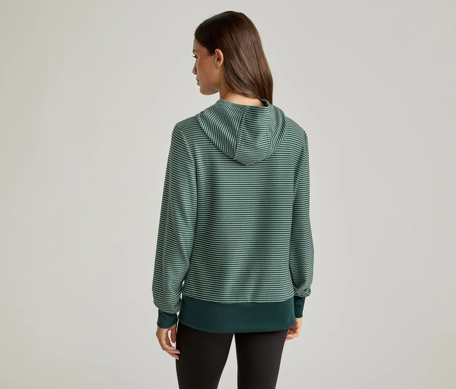 Vue arrière d'une femme aux cheveux bruns portant un sweat à capuche rayé vert et un legging noir.