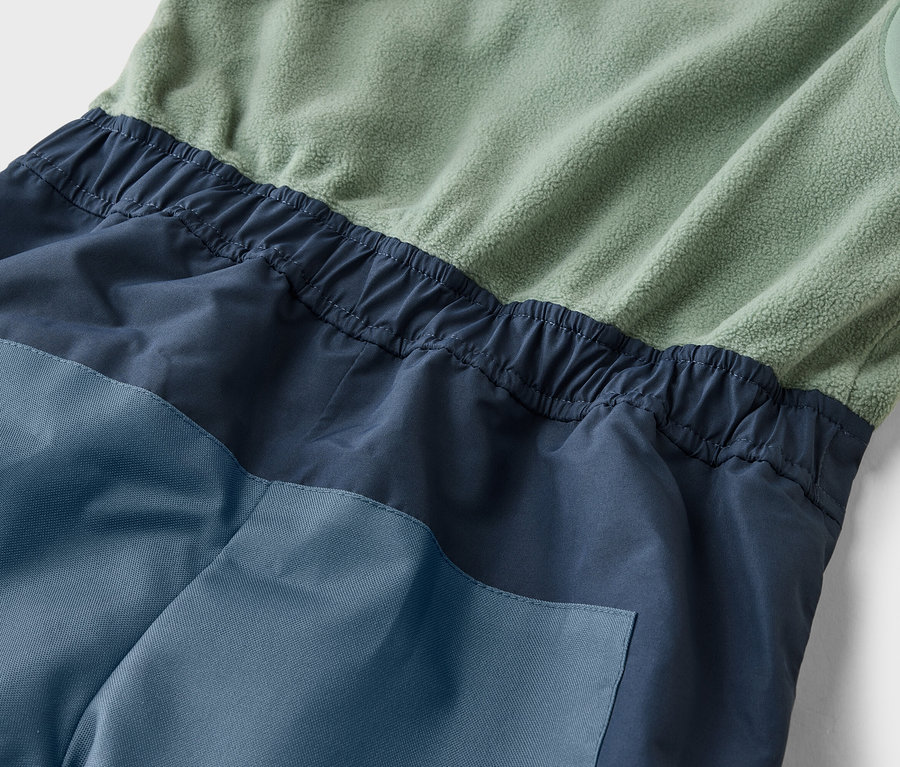 Gros plan sur une combinaison sans manches dans les tons vert, marine et bleu avec une taille élastique.
