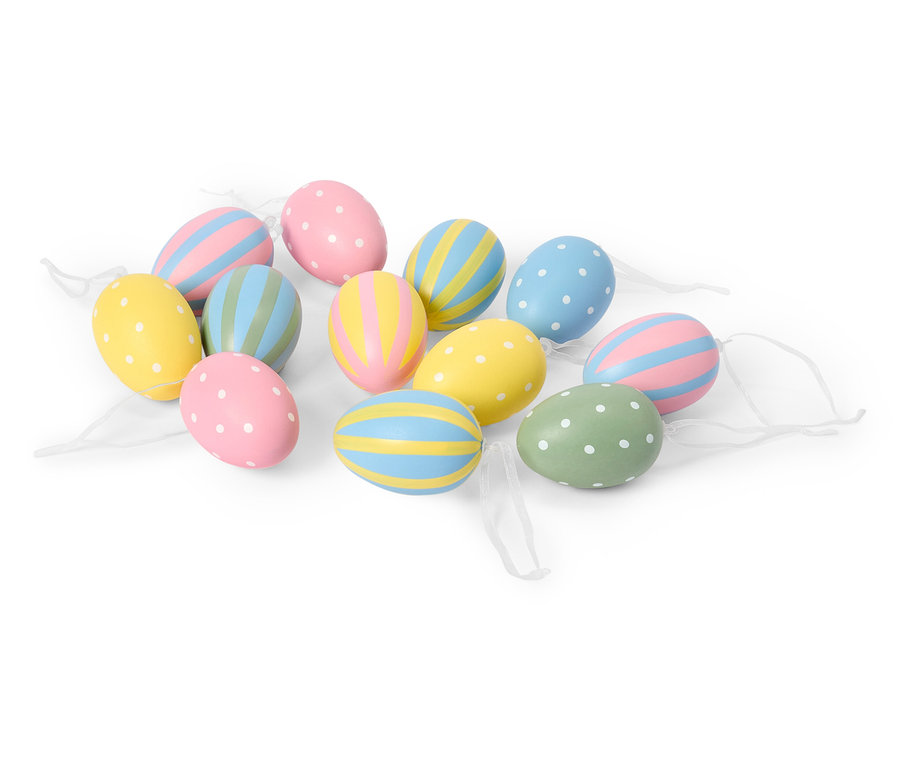 Plusieurs œufs de Pâques pastel avec des motifs à pois et à rayures sont posés sur un fond blanc.
