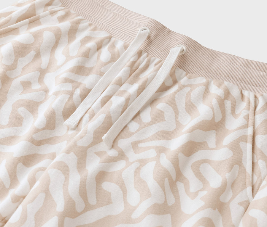 Gros plan d'un pantalon beige à motifs avec un cordon blanc.