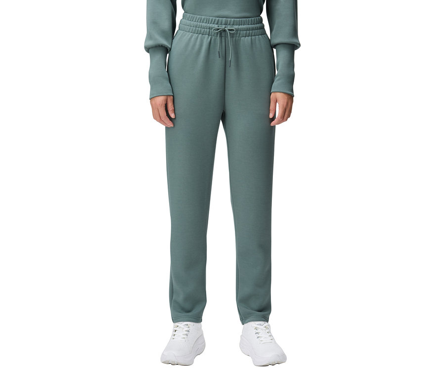 Une personne porte un pantalon de survêtement vert et des baskets blanches.