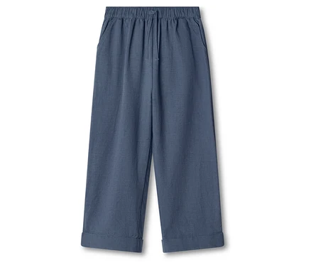 Un pantalon ample bleu avec un élastique et un cordon de serrage est visible sur un fond blanc.
