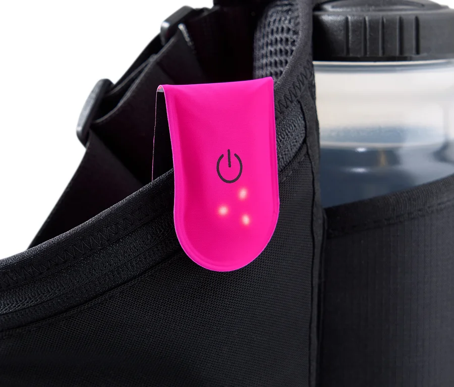 Gros plan sur une ceinture de course noire, à laquelle est attachée une lampe clip rose avec un symbole d'alimentation et trois points lumineux. Une bouteille d'eau est dans une poche en filet.