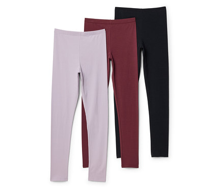 Trois leggings lilas, bordeaux et noirs sont superposés sur un fond blanc.