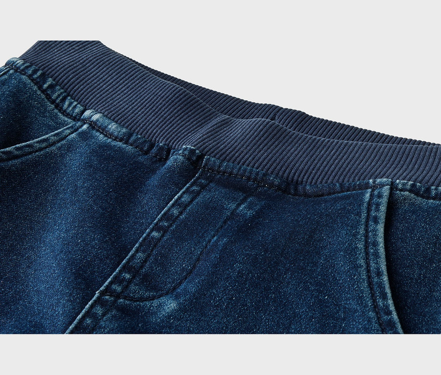 Gros plan d'un jean bleu foncé avec une taille élastique côtelée bleu marine et des poches avant.