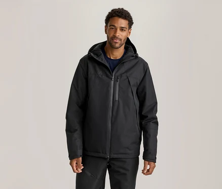 Homme portant une veste noire à capuche, un t-shirt bleu foncé et un pantalon noir.