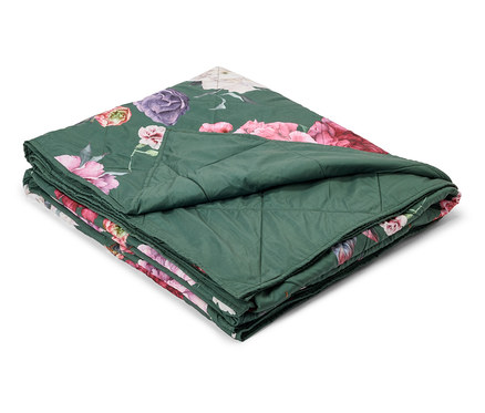 Couverture matelassée verte pliée avec un motif floral rose, violet et blanc.