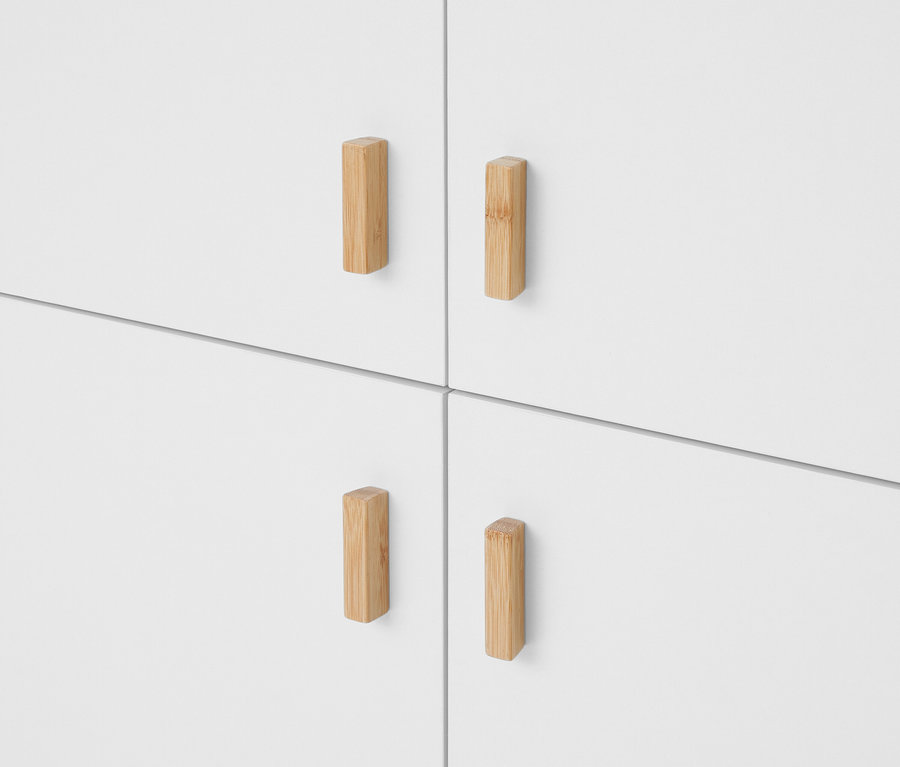 Quatre façades de portes d'armoire ou de tiroirs blanches, chacune dotée d'une poignée verticale rectangulaire en bois clair.