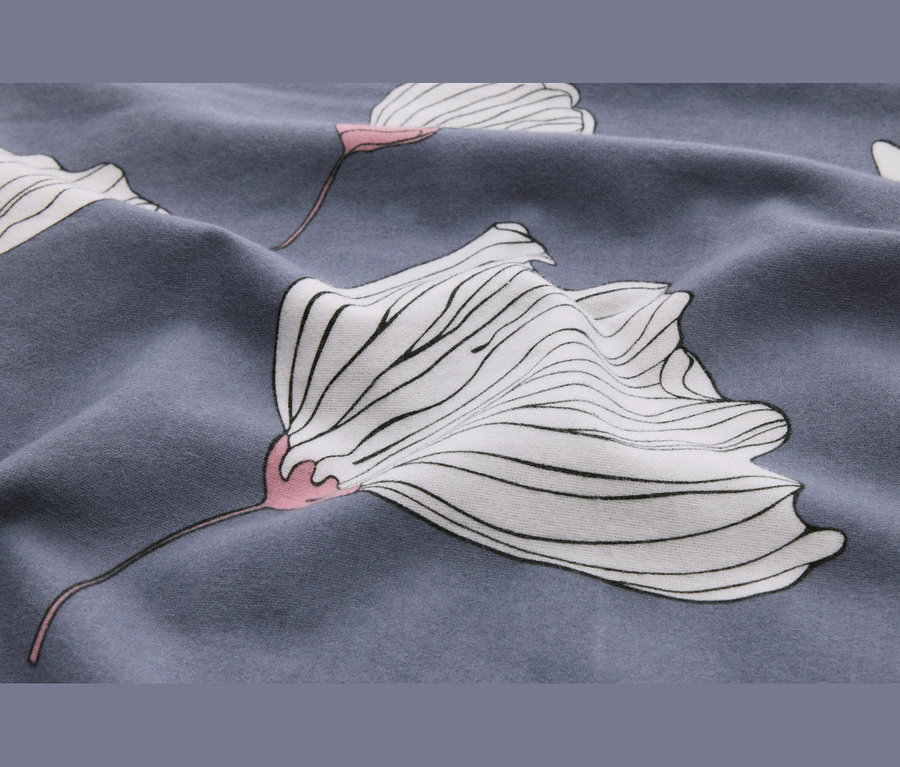Gros plan d'un tissu gris-bleu avec un motif floral blanc. Les fleurs ont des contours noirs et des centres roses, et le tissu est légèrement froissé.