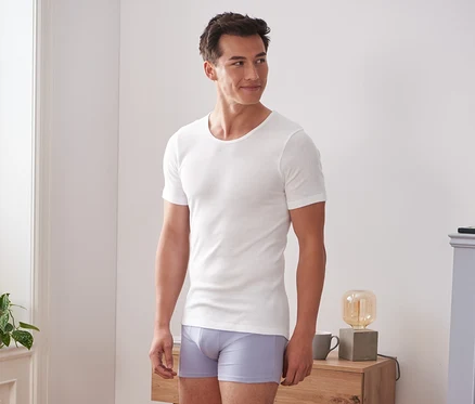 Un homme porte 2 maillots de corps finement côtelés à manches courtes et des sous-vêtements.