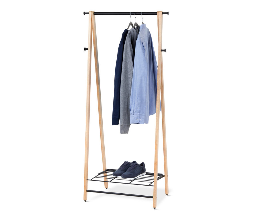 Un étendoir pliant en bois massif avec des pulls et une chemise suspendus. Des chaussures sont posées sur l'étagère inférieure.