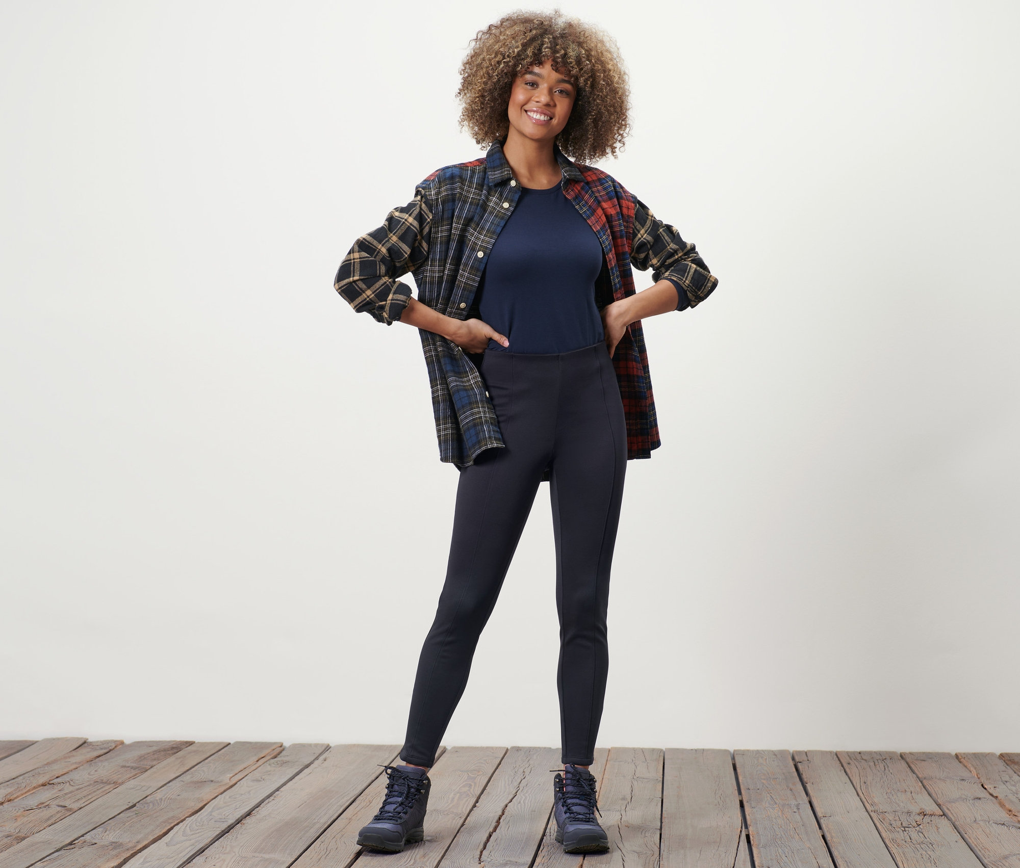 Femme posant en legging thermique, t-shirt et chemise à carreaux.