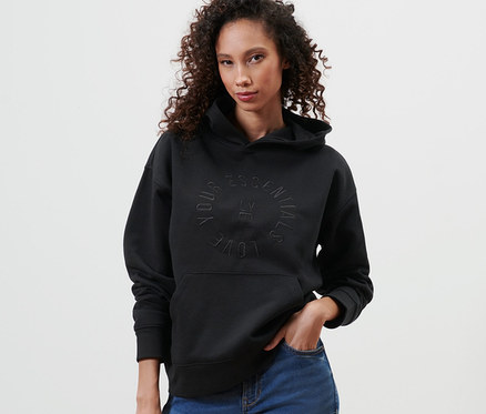 Femme posant en sweat à capuche noir et jean bleu.