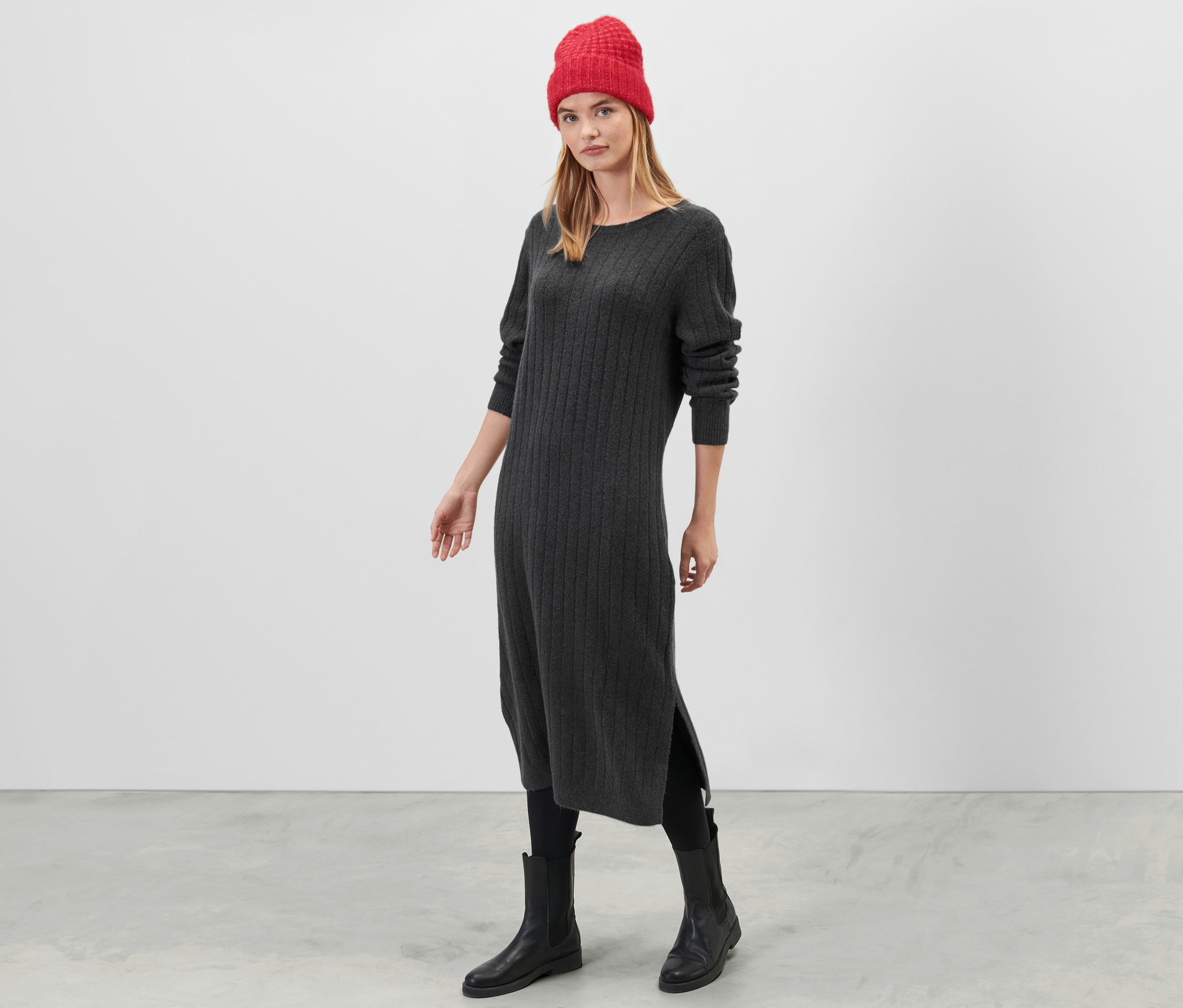 Une femme debout portant une robe en tricot côtelée grise.