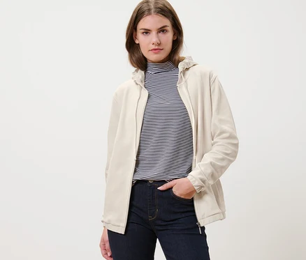 Une femme portant une jaquette en sweat blanc crème et un jean.