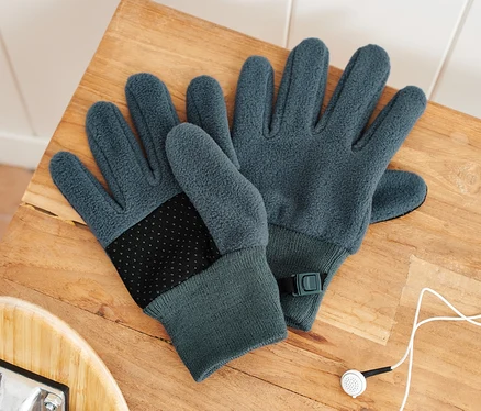 Deux gants en polaire pour enfants reposent sur un banc en bois à côté d'une planche à roulettes et d'écouteurs.