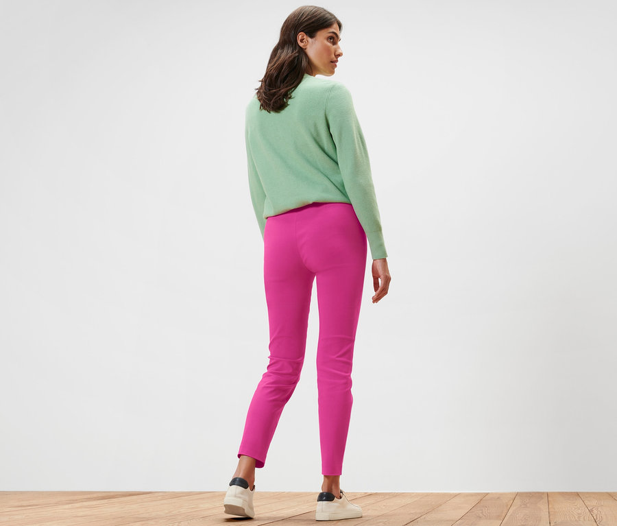 Une femme, vue de dos, porte un pantalon stretch rose vif.