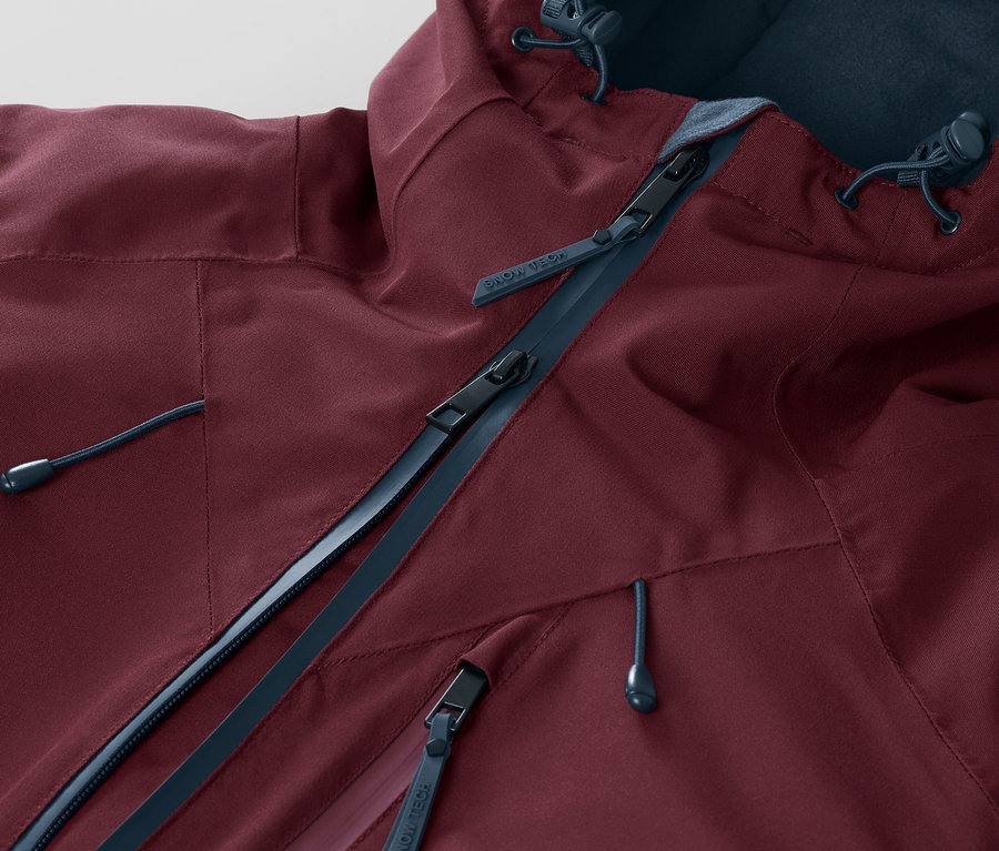 Gros plan sur une veste de ski et de snowboard bordeaux avec fermeture éclair et capuche.