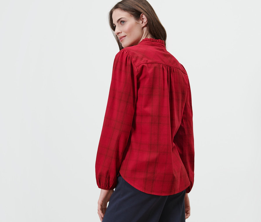 Une femme regardant par-dessus son épaule portant une blouse à carreaux avec lavallière.