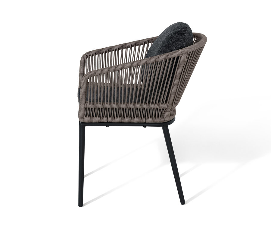 Gros plan sur un fauteuil pour table à manger avec tressage textile et coussin gris.