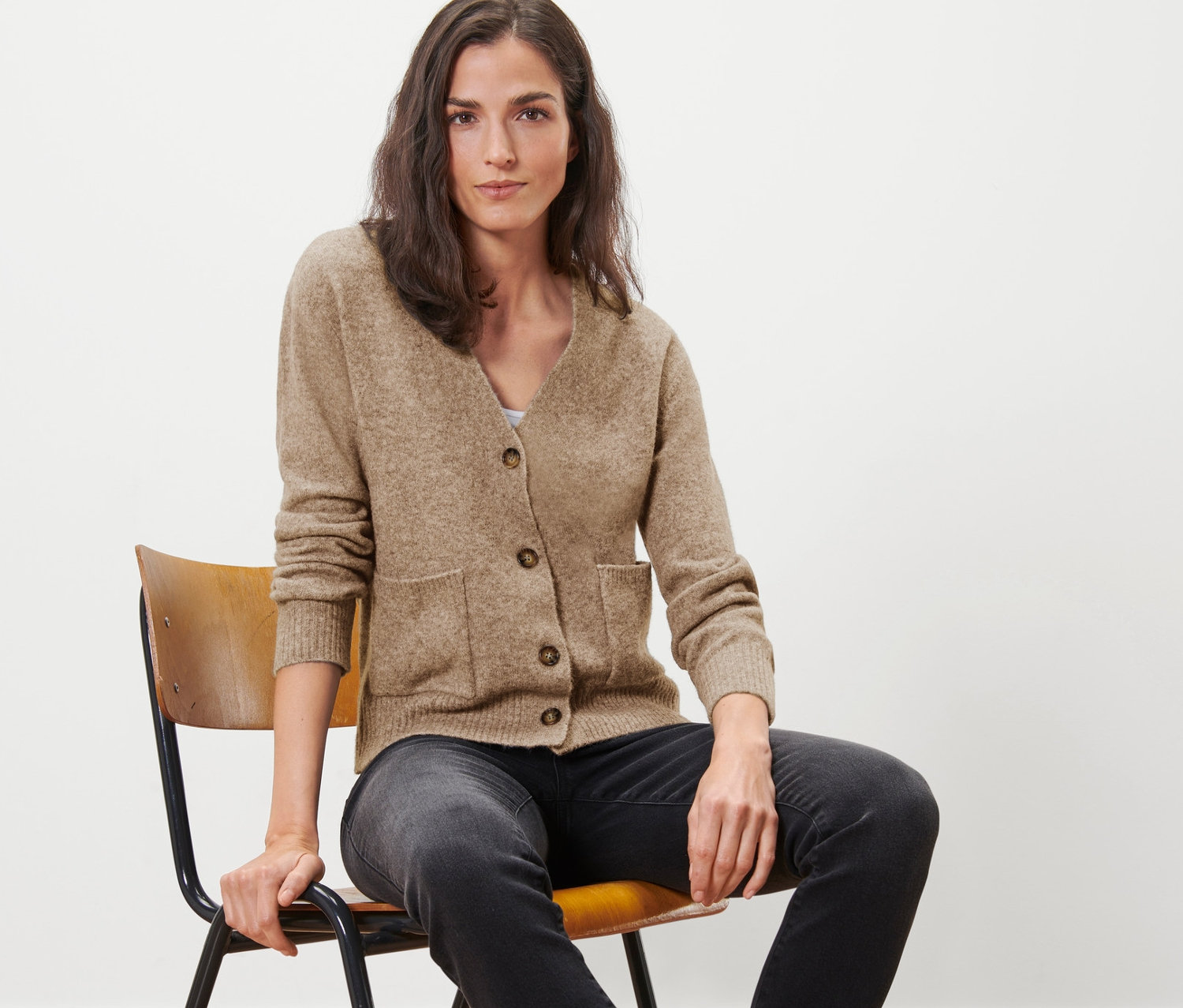 Femme assise sur une chaise portant une jaquette en maille avec de la laine.