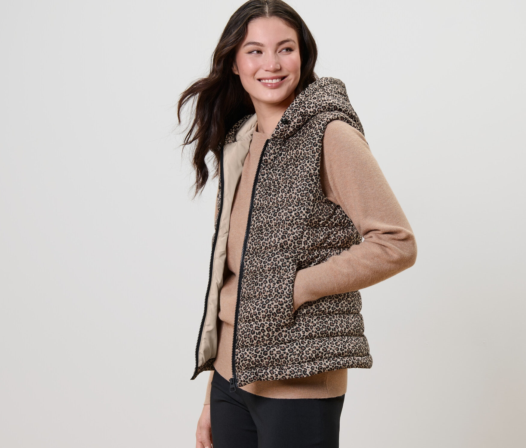 Femme posant dans un gilet sans manche matelassé imprimé à capuche.