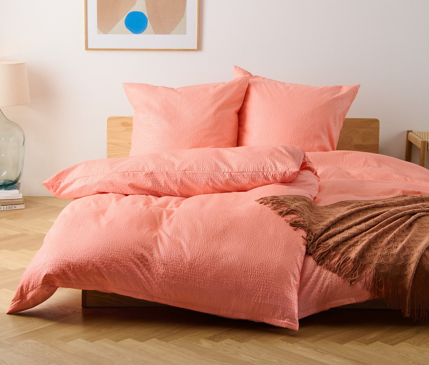 Une vue de face d'un lit avec des parures de lit en seersucker de taille standard et de grande taille, de couleur pêche.