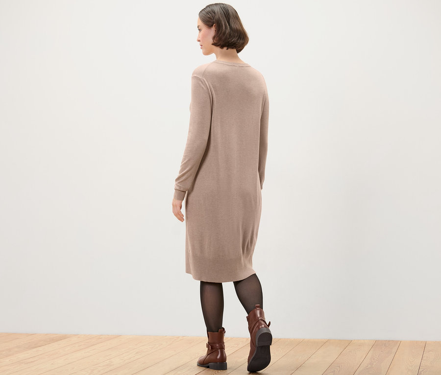 Femme portant une robe en maille fine, des collants noirs et des bottes marron.