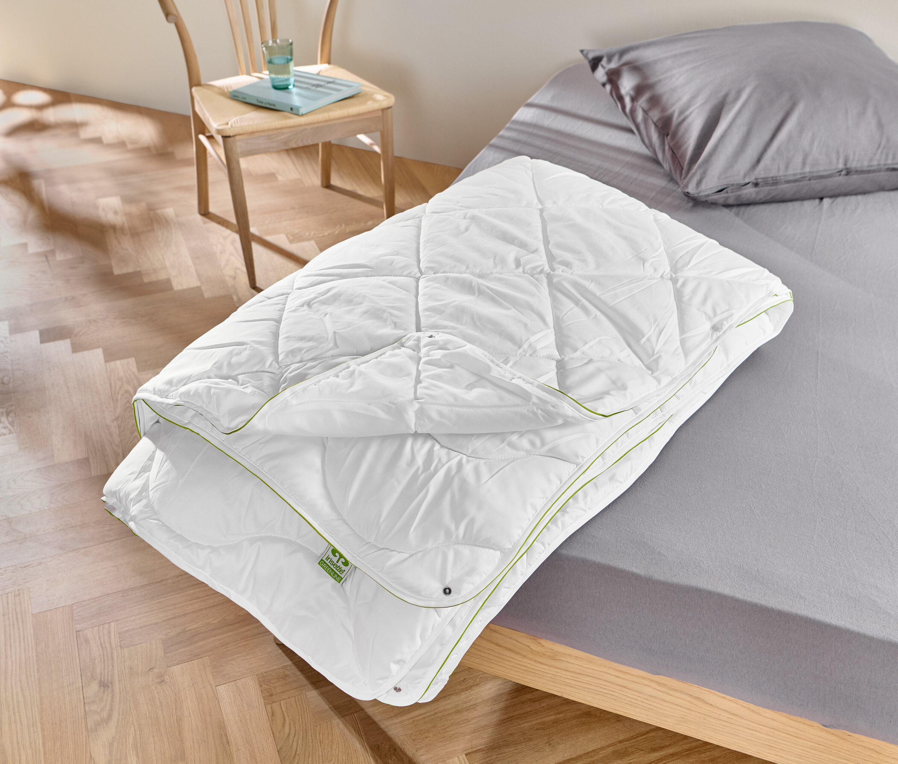 Une couette blanche irisette® greenline est posée sur un lit.