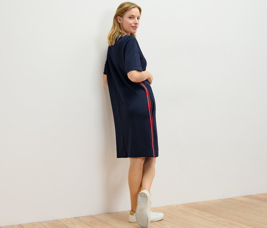 Femme regardant par-dessus son épaule et posant dans une robe en sweat à galons.