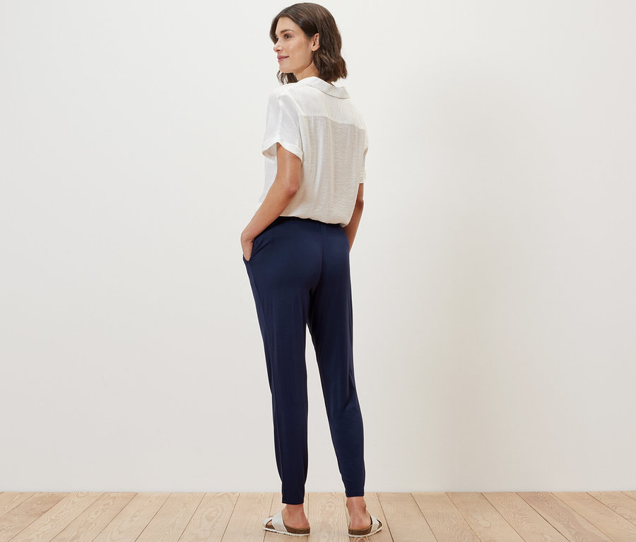 Une femme, vue de dos, porte un pantalon en jersey bleu foncé.