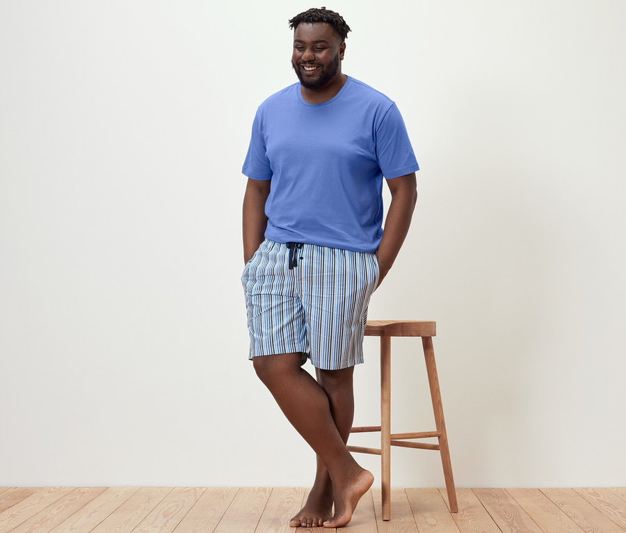 Un homme s'appuie sur un tabouret et porte un pyjashort.