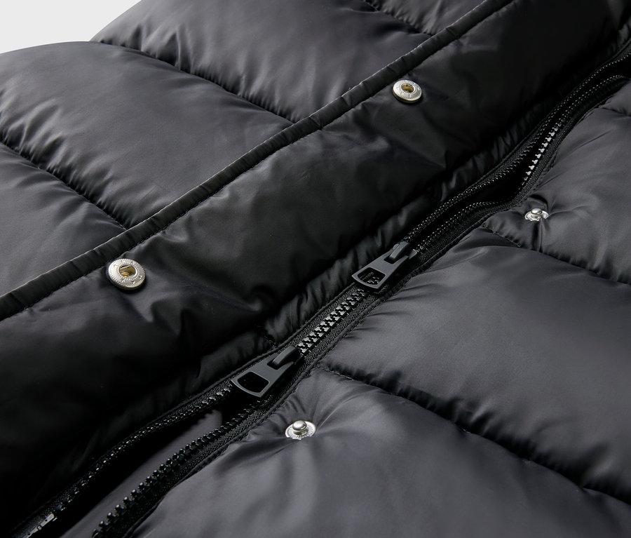Gros plan sur une veste matelassée noire avec fermeture éclair et boutons-pression.